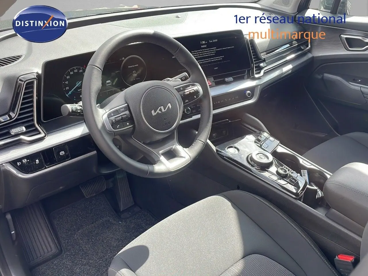 Intérieur du Kia Sportage 2025 vu côté conducteur, tableau de bord moderne avec écran tactile et volant multifonction noir.