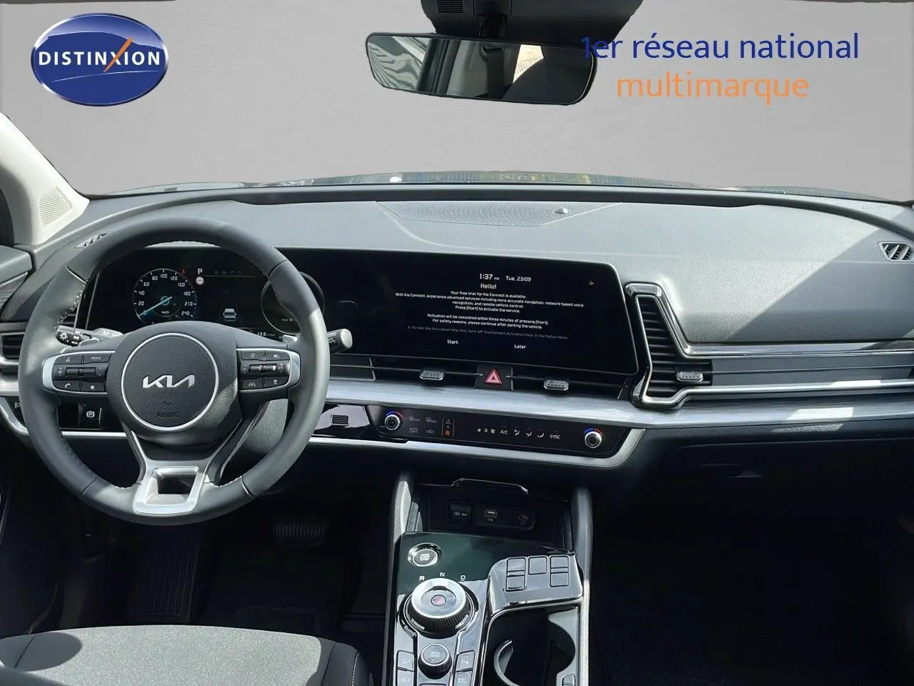 Vue intérieure du tableau de bord et volant du Kia Sportage 2025 gris foncé, avec écran tactile et commandes modernes.