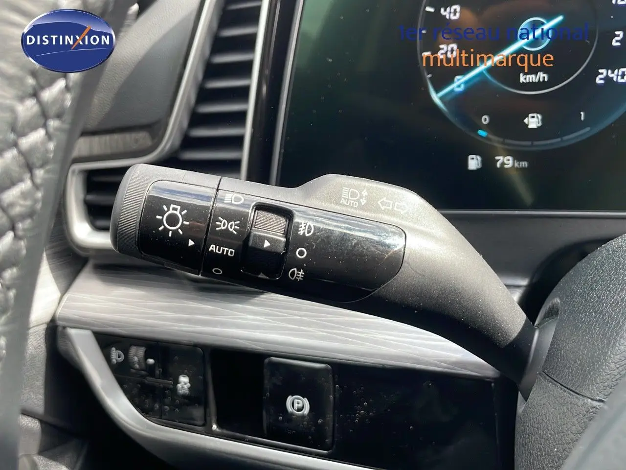 Gros plan sur la manette des feux et clignotants côté gauche du volant du KIA Sportage gris foncé 2025 avec tableau de bord digital.