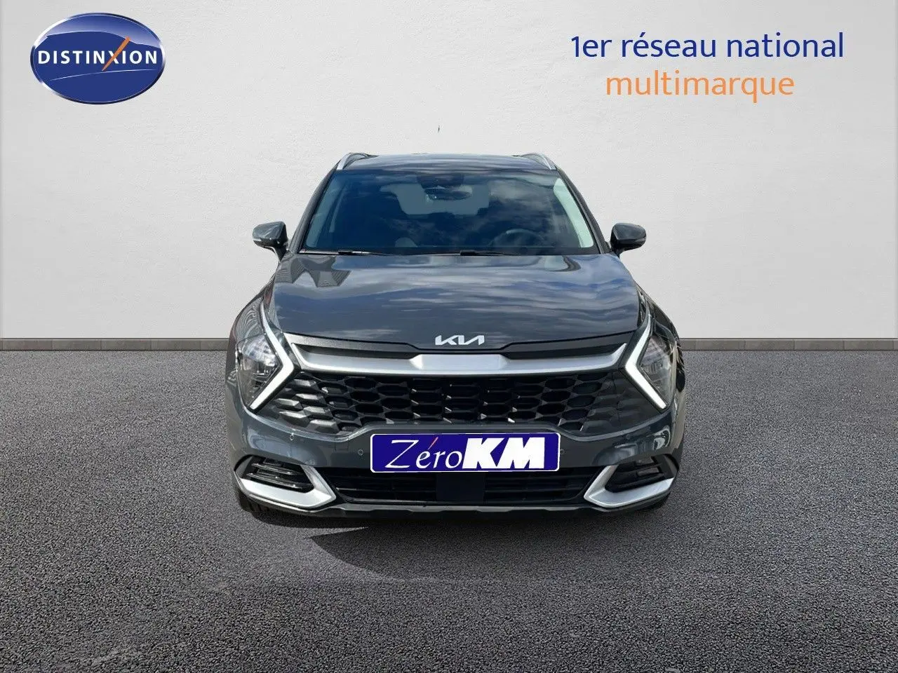 Vue frontale d'un Kia Sportage gris foncé métal 2025 avec calandre large et phares LED en forme de flèche.