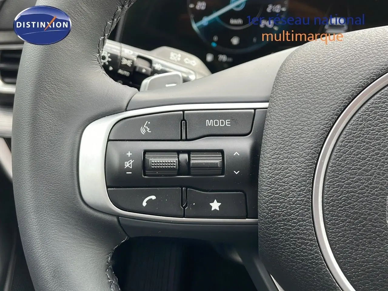 Gros plan sur les commandes multifonctions à gauche du volant en cuir noir du Kia Sportage gris foncé 2025.