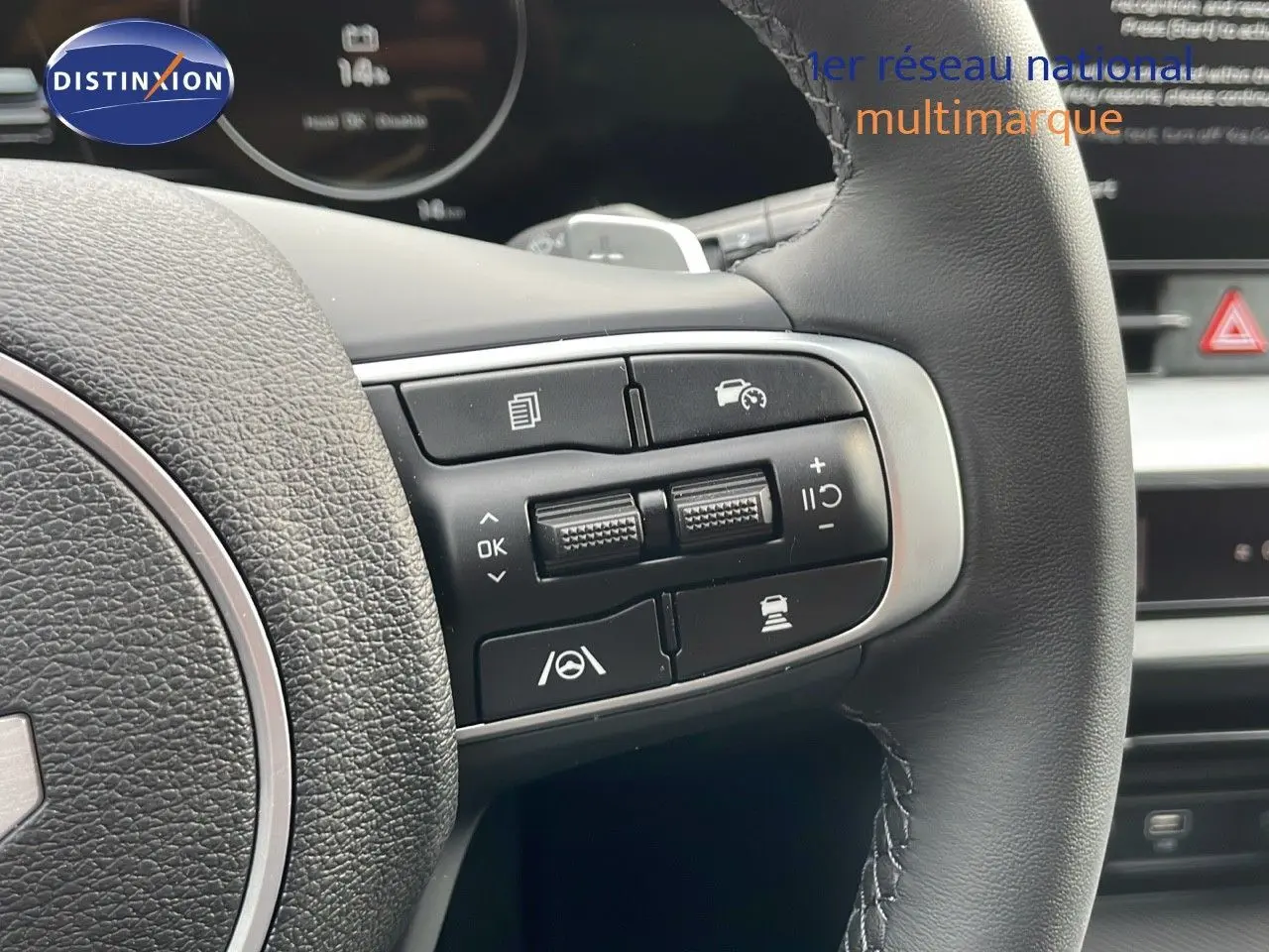 Gros plan sur les commandes au volant en cuir noir du Kia Sportage gris foncé 2025, mettant en valeur les boutons multifonctions.