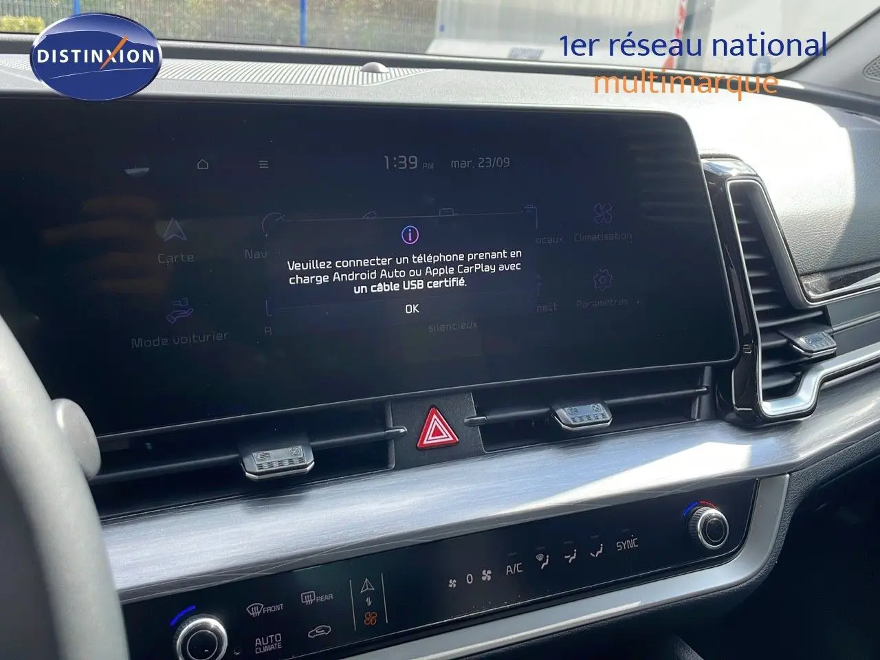 Tableau de bord intérieur du Kia Sportage 2025, écran tactile central et commandes climatisation visibles, finition moderne noire.