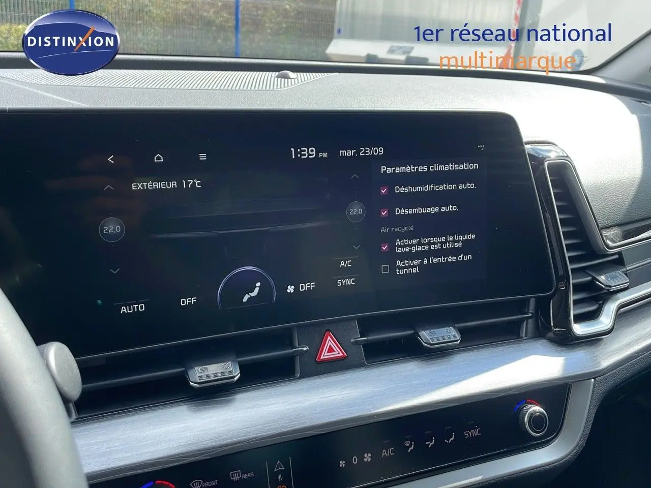 Tableau de bord du Kia Sportage 2025 gris foncé, vue rapprochée sur l'écran tactile et commandes de climatisation.