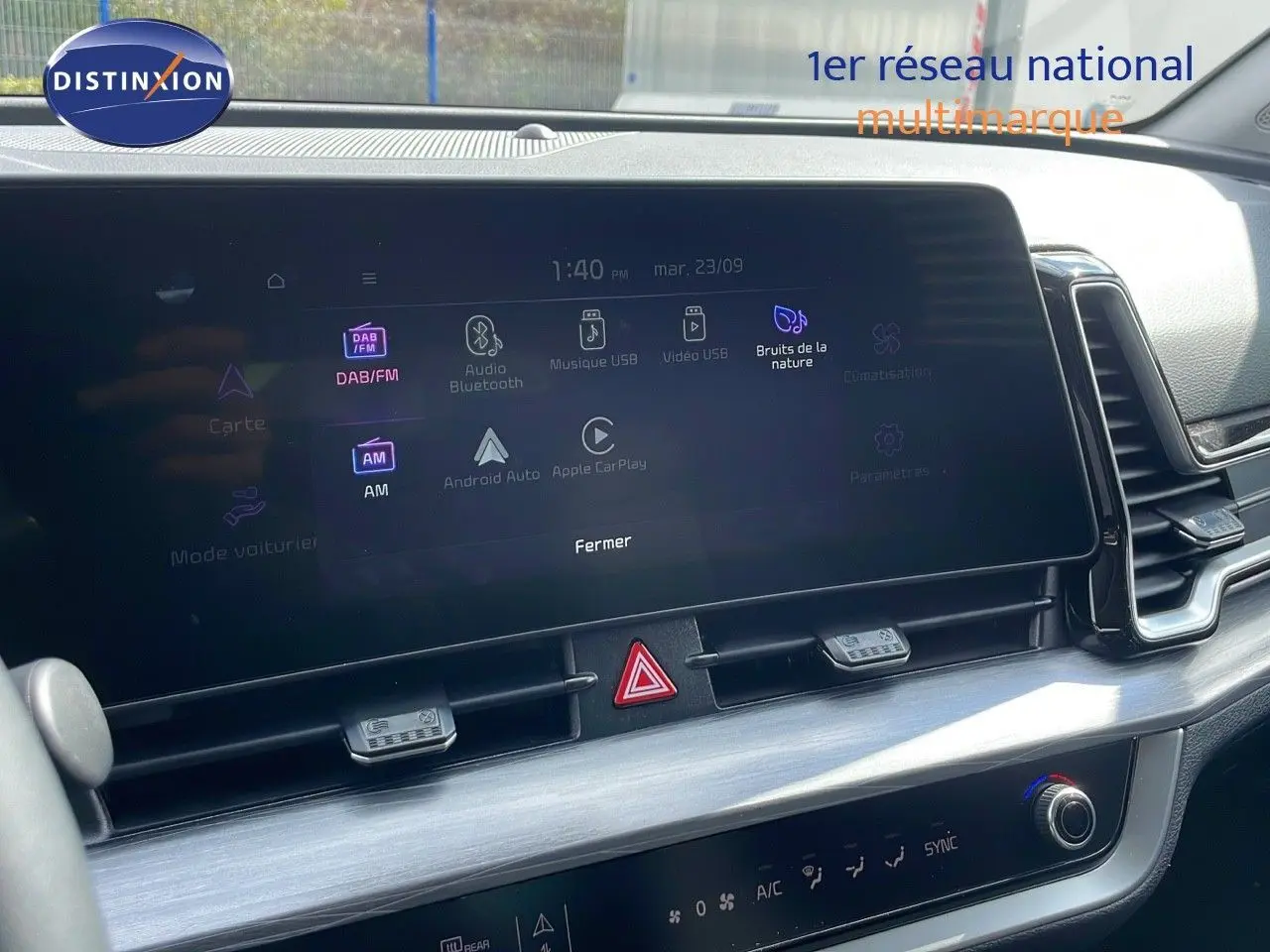 Écran tactile central du tableau de bord du Kia Sportage gris foncé 2025, affichant les options multimédia et climatisation.