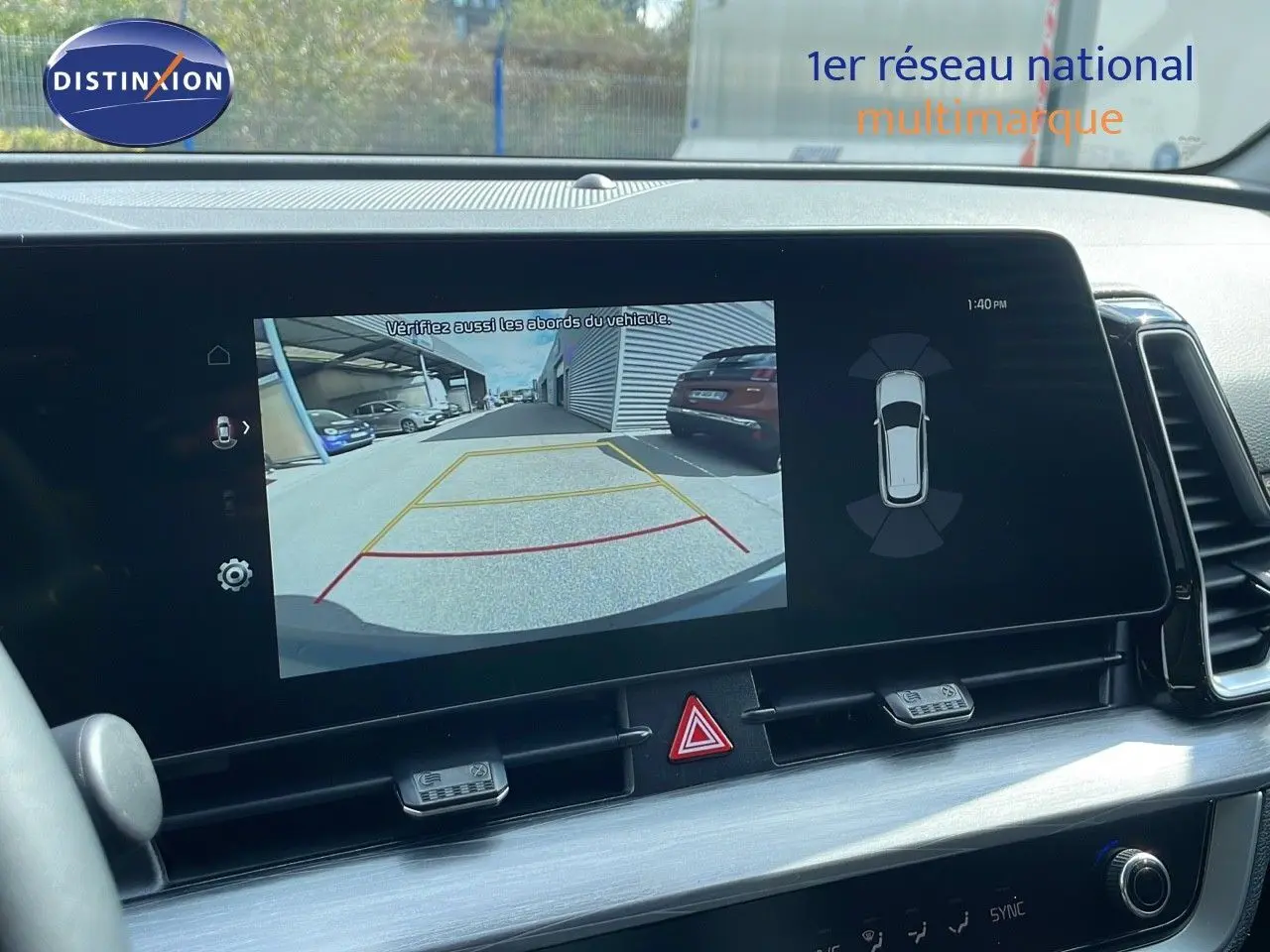 Écran tactile intérieur du Kia Sportage 2025 montrant la caméra de recul avec vue arrière et alertes de stationnement.