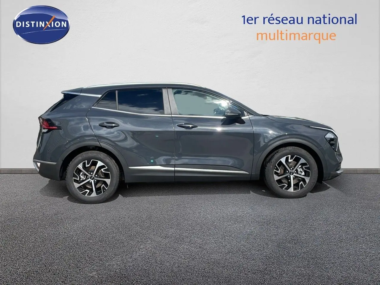 Profil côté gauche du SUV KIA SPORTAGE gris foncé métallisé avec jantes alliage bicolores sur fond neutre.
