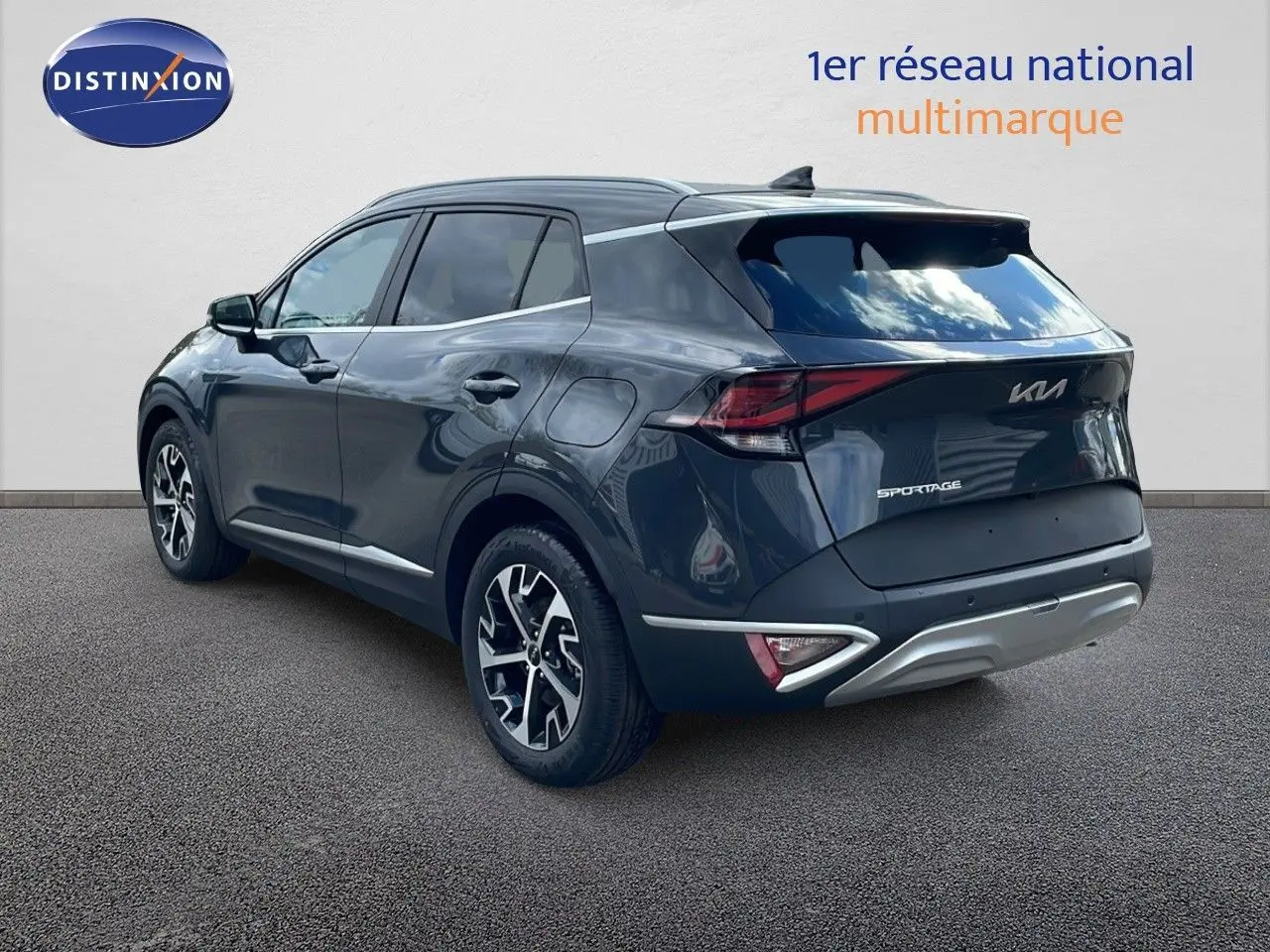 KIA Sportage gris foncé métal vu en 3/4 arrière côté gauche, avec jantes alliage et feux LED distinctifs.
