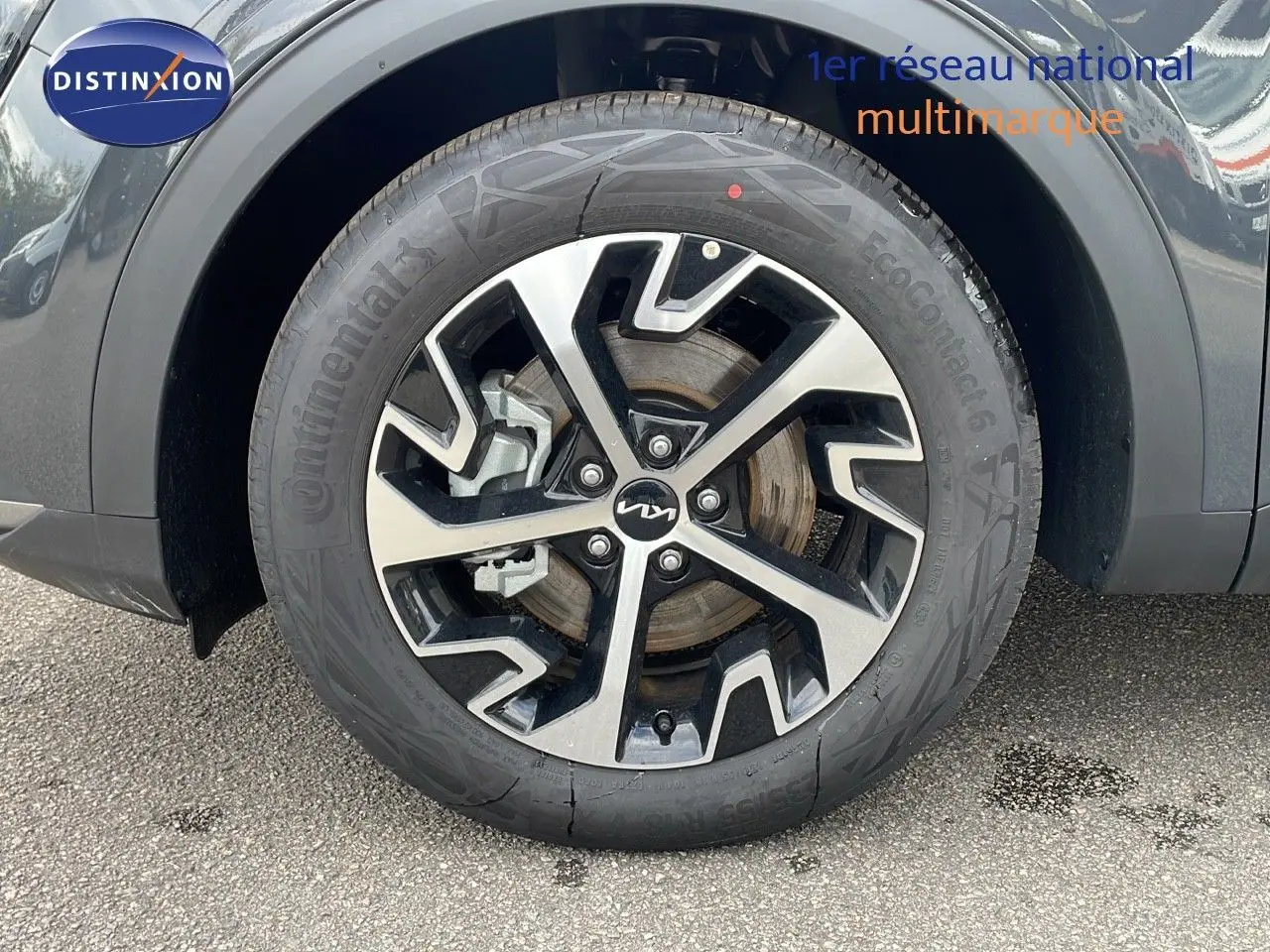 Gros plan sur la roue avant gauche du KIA SPORTAGE gris foncé métal avec jante alliage bicolore au design moderne.