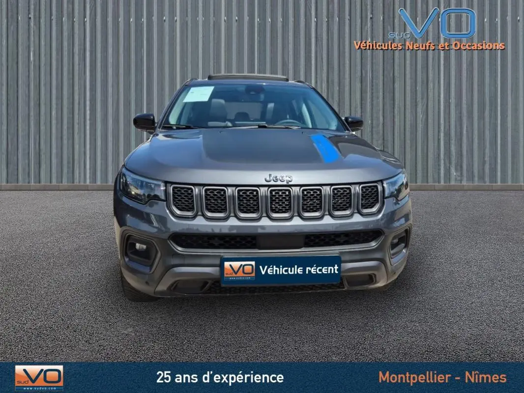 Vue frontale d'un Jeep Compass gris foncé 2022, version hybride Trailhawk avec calandre distinctive à sept fentes.
