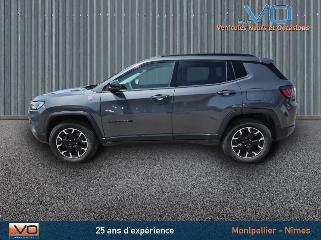 Profil côté gauche du Jeep Compass gris foncé Trailhawk 2022, SUV hybride avec jantes noires et détails robustes.