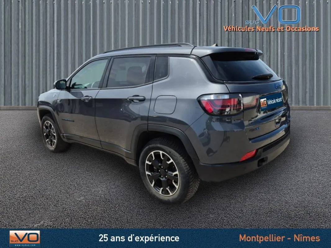 Jeep Compass gris foncé vu en 3/4 arrière droit, version hybride 4xe Trailhawk avec jantes noires distinctives.