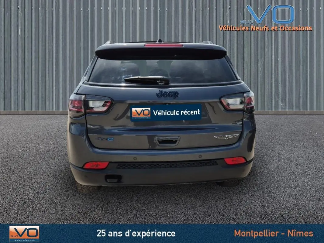 Vue arrière d'un Jeep Compass gris foncé 2022 Trailhawk avec badges 4xe et eAWD sur un sol goudronné.