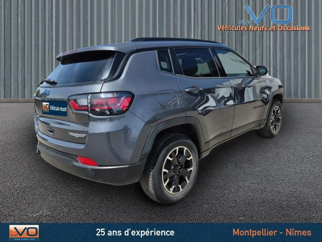 Vue 3/4 arrière droite d'un Jeep Compass gris foncé Trailhawk 2022 avec jantes alliage et vitres teintées.