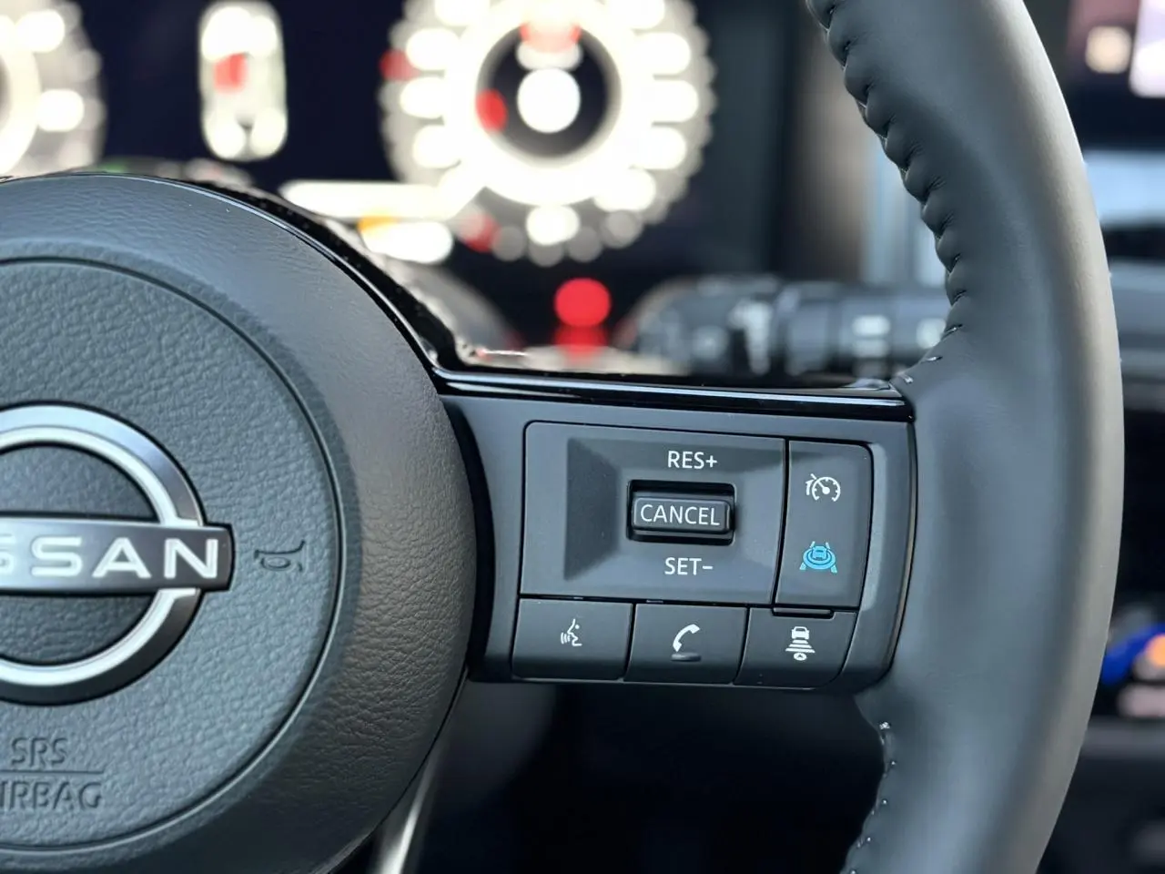 Gros plan sur le côté droit du volant cuir noir du Nissan Qashqai III avec commandes de régulateur et aides à la conduite.