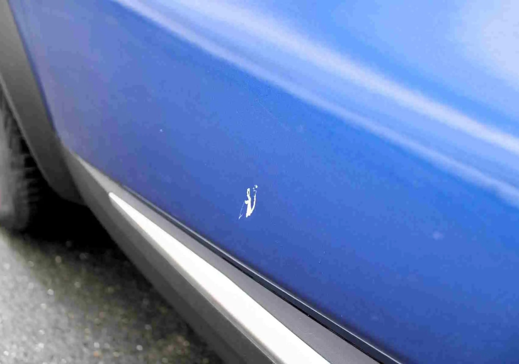 Gros plan sur la portière côté gauche d'une Renault Symbioz bleu iron metal avec une rayure visible.