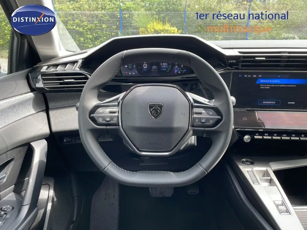 Vue intérieure centrée sur le volant cuir noir et le tableau de bord numérique de la Peugeot 308 SW Hybrid 2025.