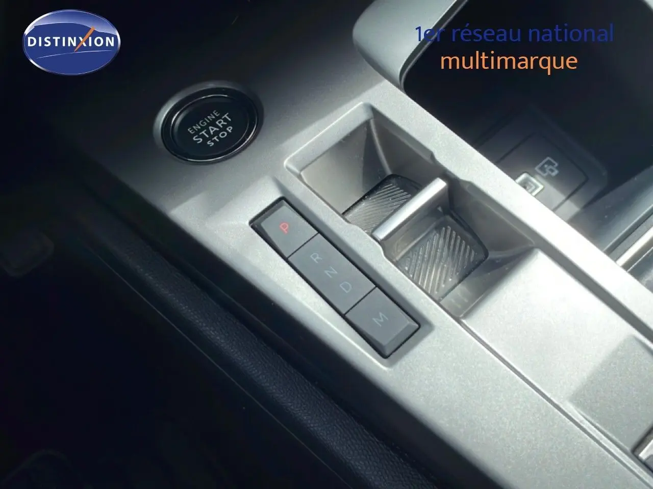 Gros plan sur la console centrale argentée de la Peugeot 308 SW Hybrid 2025 avec bouton start/stop et levier de boîte automatique.