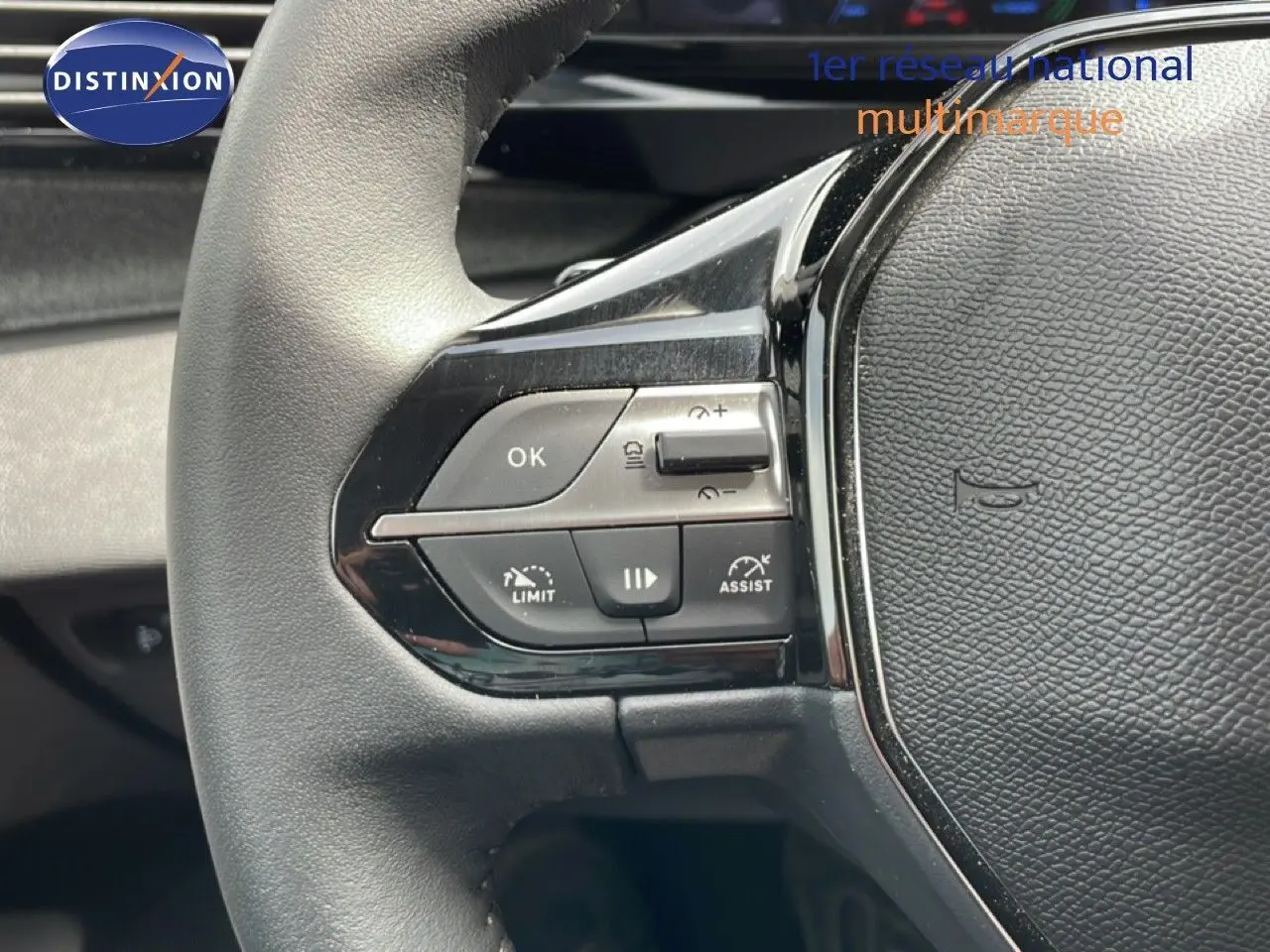 Gros plan sur les commandes gauche du volant cuir noir du Peugeot 308 SW Hybrid 2025, boutons de régulateur et assistant de conduite.