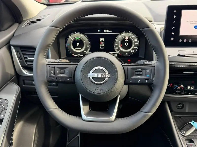 Vue intérieure centrée sur le volant du Nissan Qashqai Hybrid e-POWER 2025 avec tableau de bord numérique et commandes intégrées.