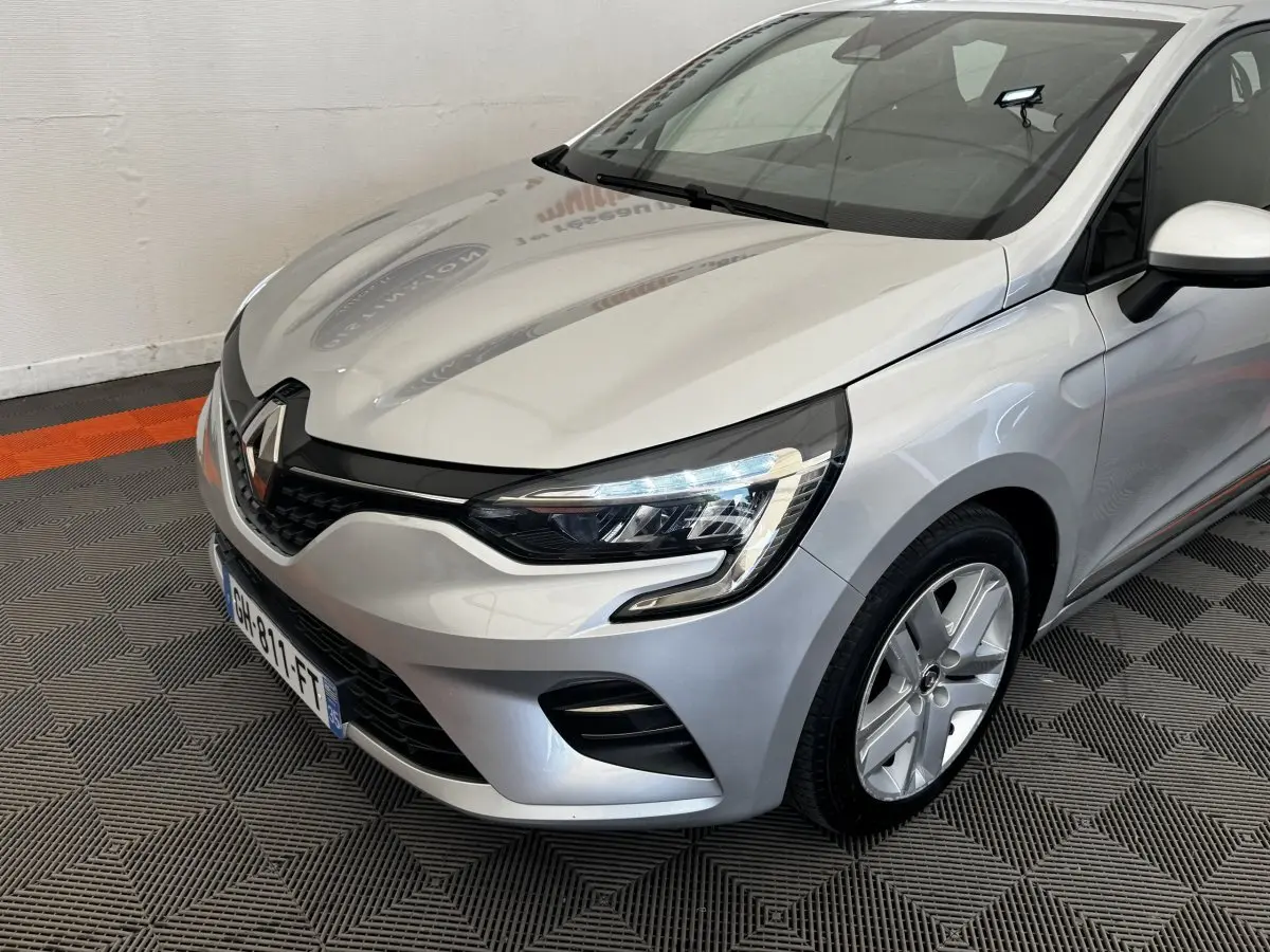 Vue 3/4 avant droite d'une Renault Clio Business E-TECH 140 gris clair avec phares LED et jantes alliage.