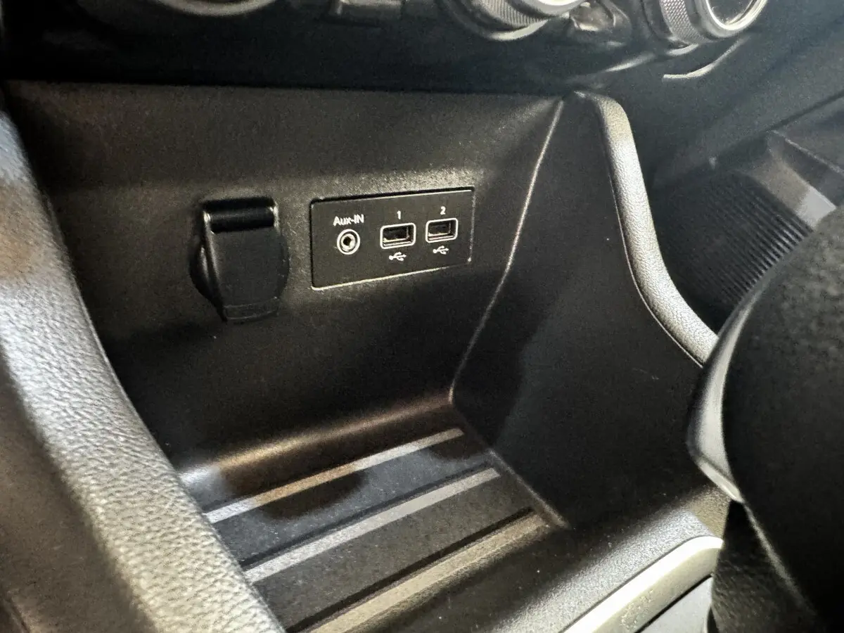 Vue rapprochée de la console centrale noire de la Renault Clio Business E-TECH 140, montrant les ports USB et prise auxiliaire.