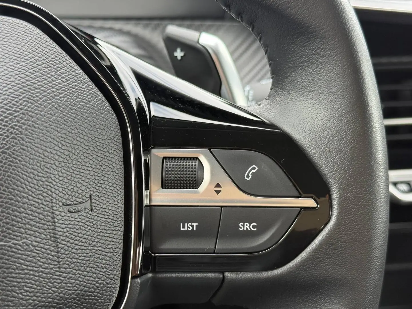 Gros plan sur les commandes audio et téléphone au volant noir du Peugeot 208 1.2 Hybrid 110ch Style 2025.