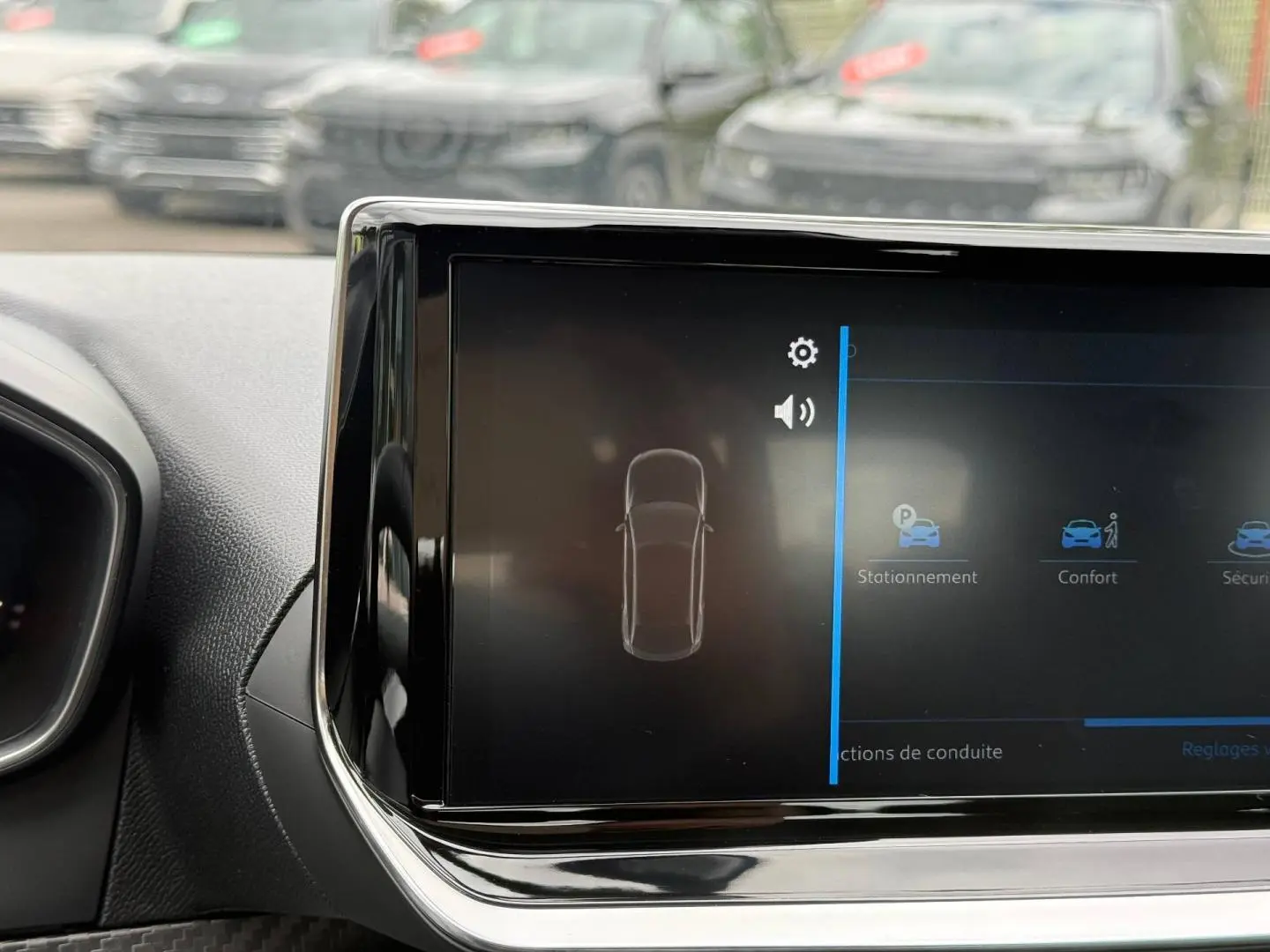 Écran tactile central de la Peugeot 208 2025 montrant les options de stationnement et confort, intérieur noir.