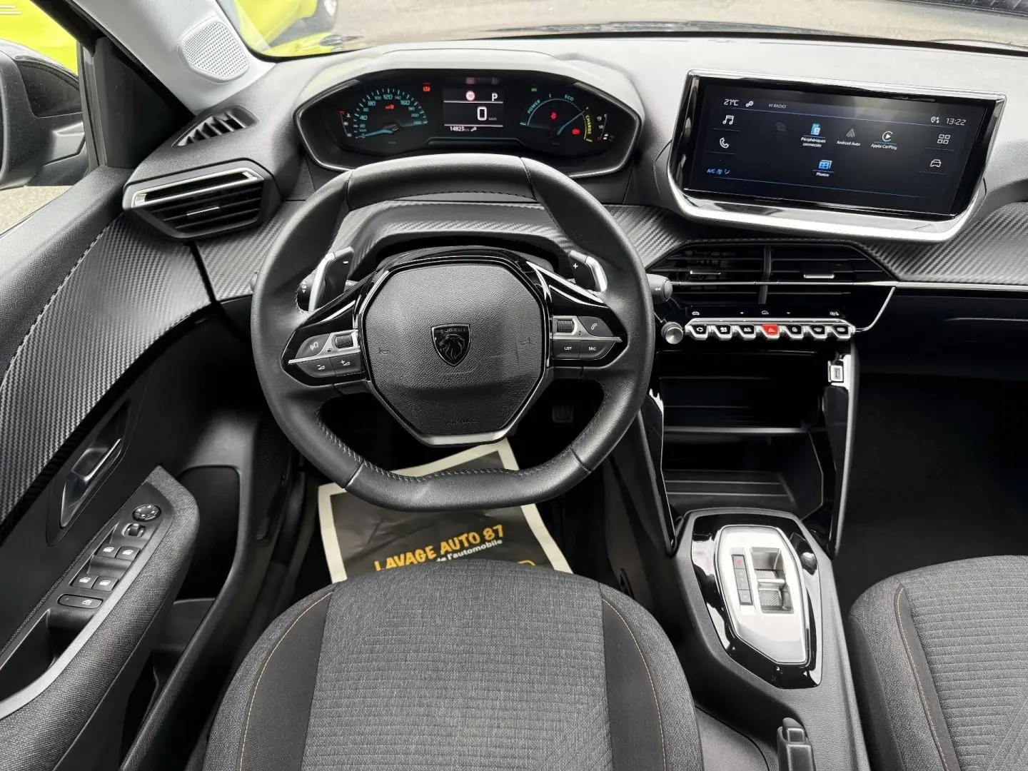 Vue intérieure avant du Peugeot 208 1.2 Hybrid 110ch Style 2025, volant cuir, tableau de bord numérique et écran tactile.