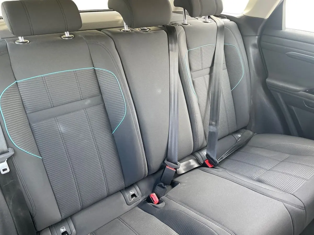 Vue intérieure sur les sièges arrière noirs du Range Rover Evoque 2020 avec surpiqûres bleues et ceintures de sécurité visibles.