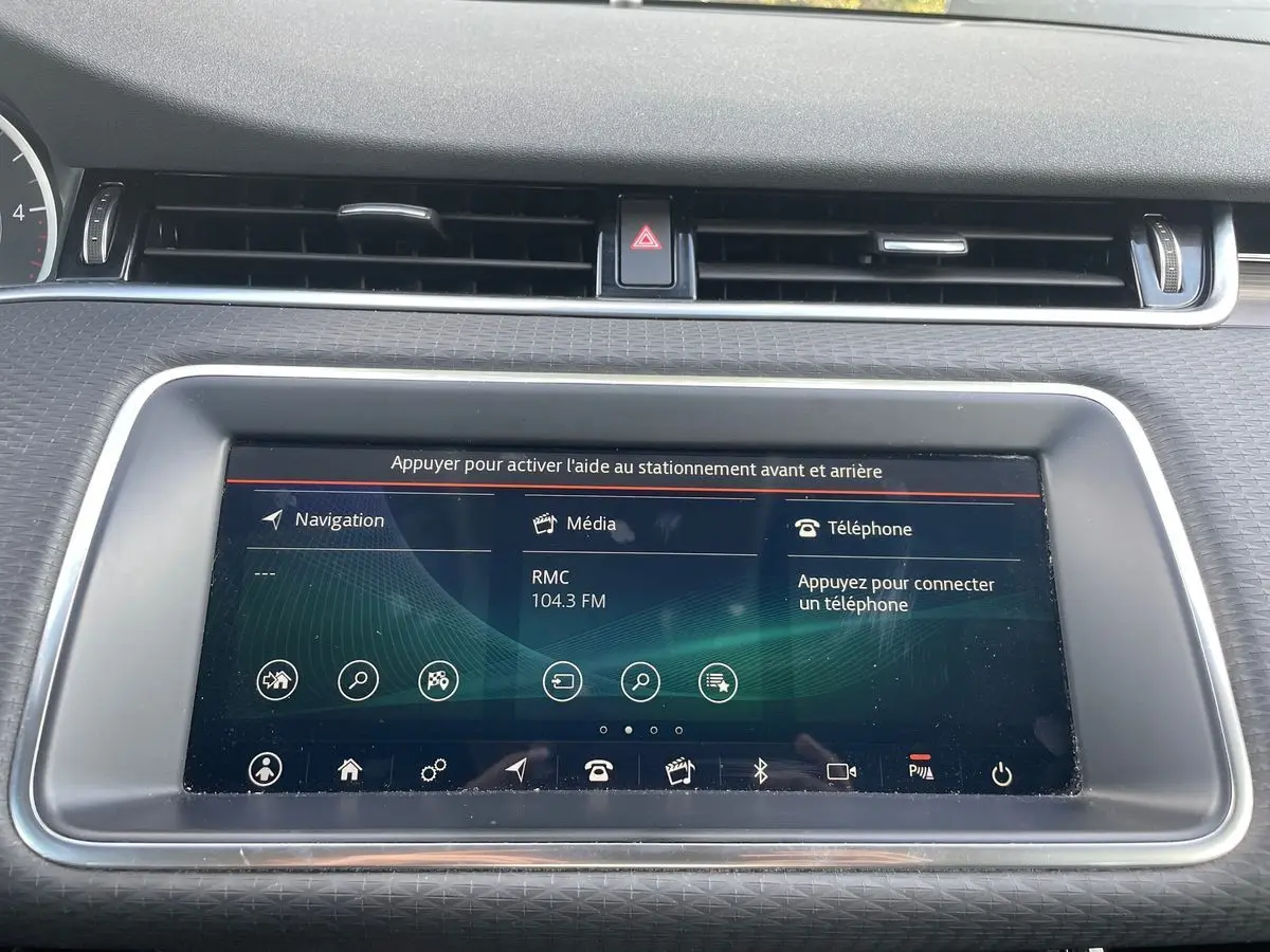 Écran tactile central du tableau de bord du Range Rover Evoque blanc, affichant navigation, média et téléphone.