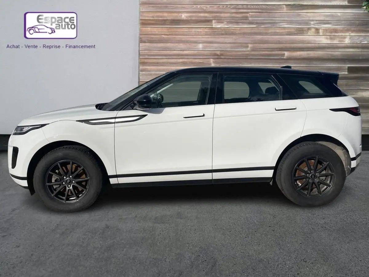 Profil côté gauche d'un Range Rover Evoque blanc 2020 avec toit noir et jantes noires sur fond urbain.