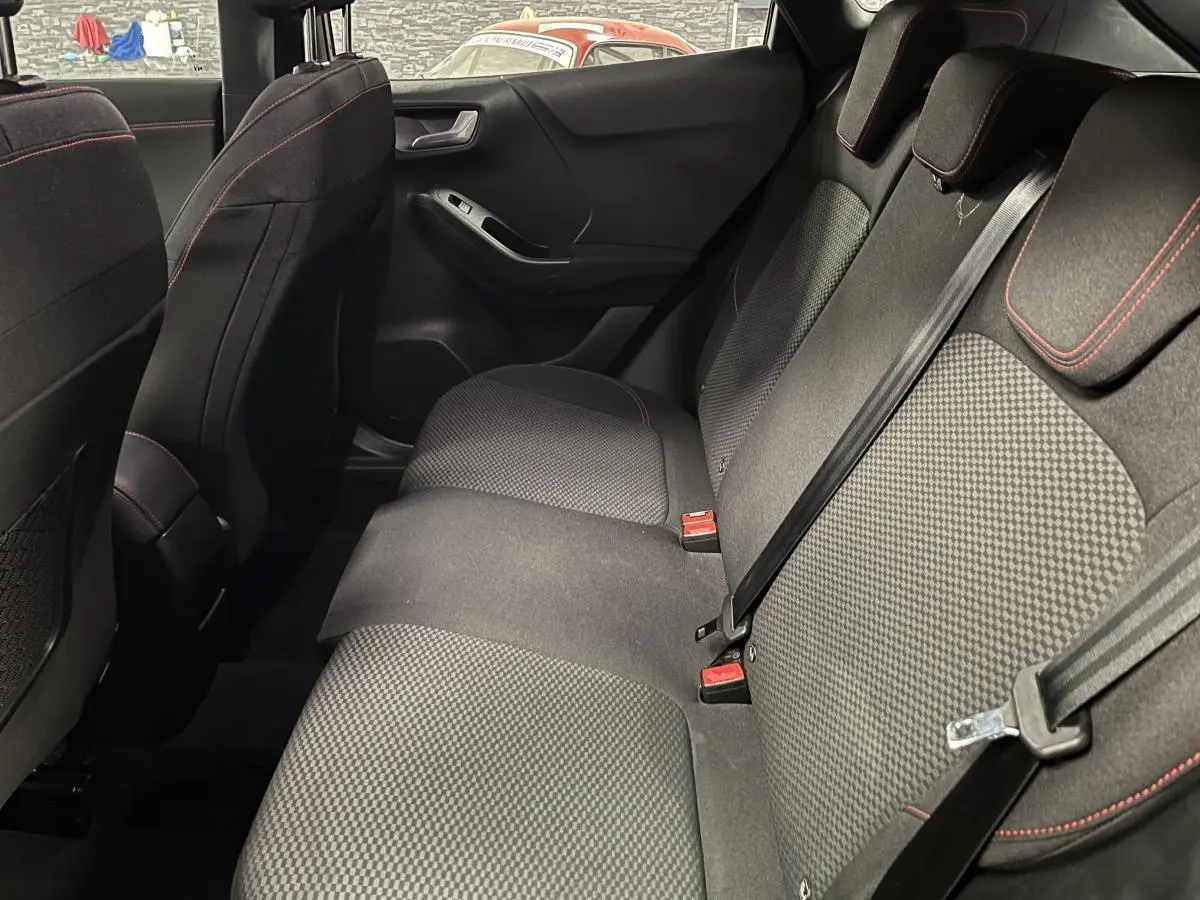 Vue intérieure côté droit de la banquette arrière noire du Ford Puma 2023 avec surpiqûres rouges et ceintures de sécurité.