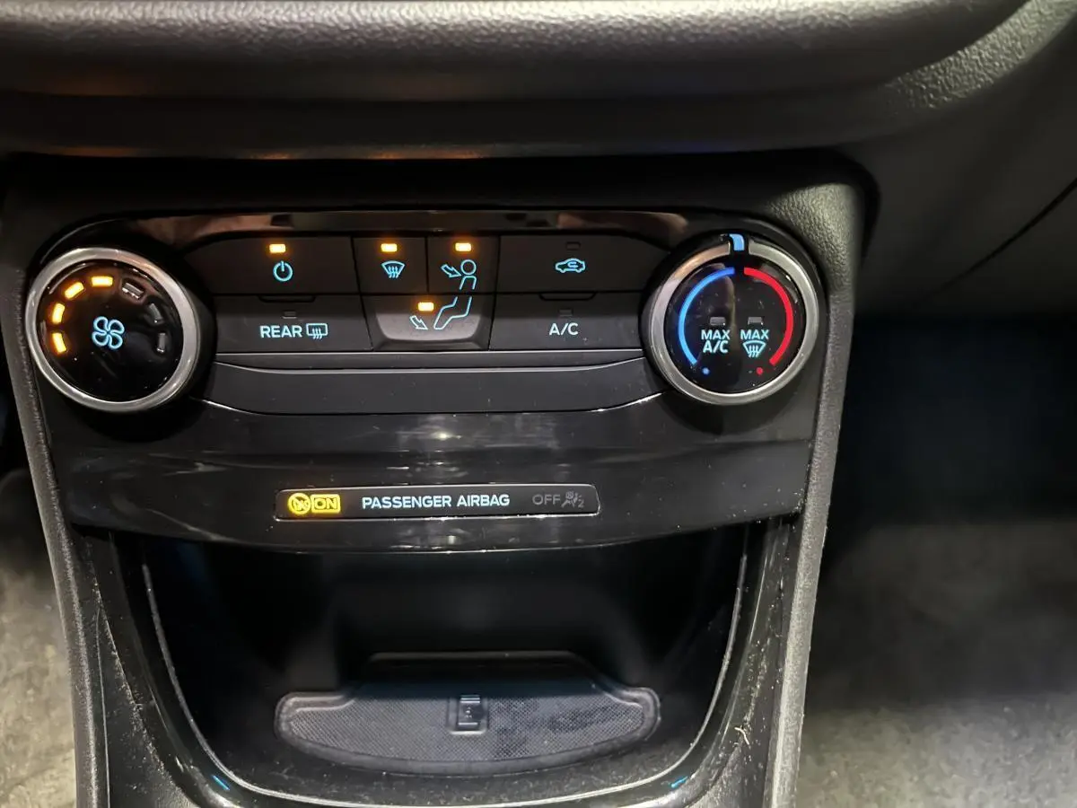 Vue rapprochée de la console centrale du Ford Puma noir 2023, montrant les commandes de climatisation et l'indicateur airbag passager.