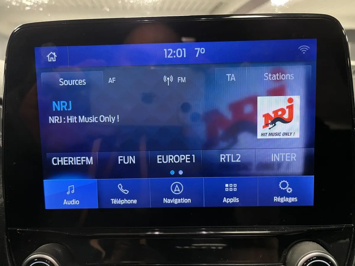 Écran tactile central du Ford Puma 2023 affichant la radio NRJ avec interface bleue et commandes audio visibles.