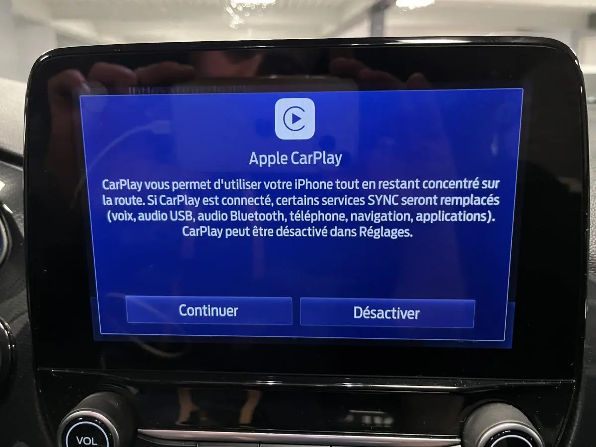 Écran tactile central affichant l'interface Apple CarPlay dans un Ford Puma noir, intérieur moderne et épuré.