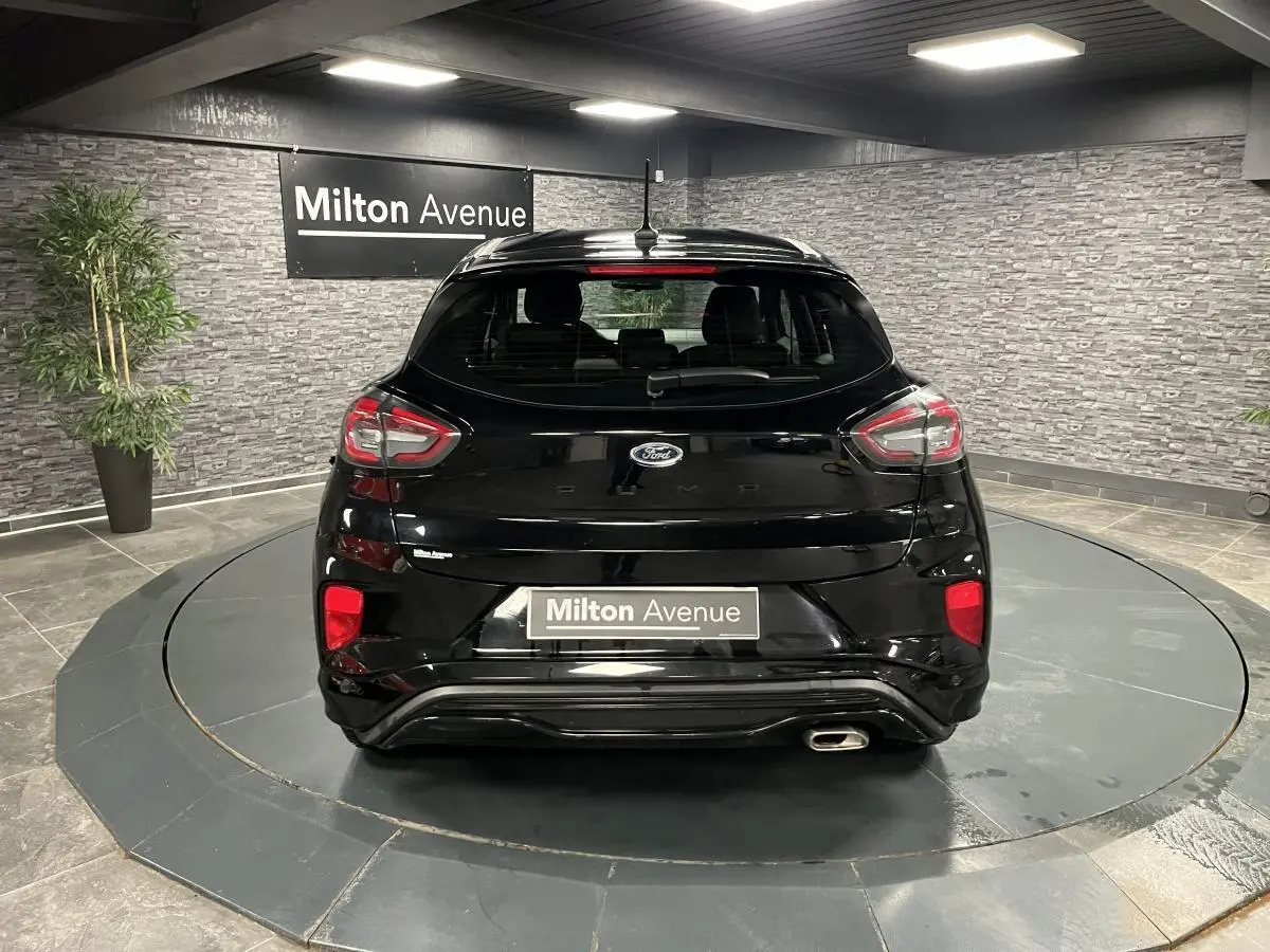 Vue arrière du Ford Puma noir brillant avec sortie d'échappement chromée et feux arrière LED en intérieur showroom
