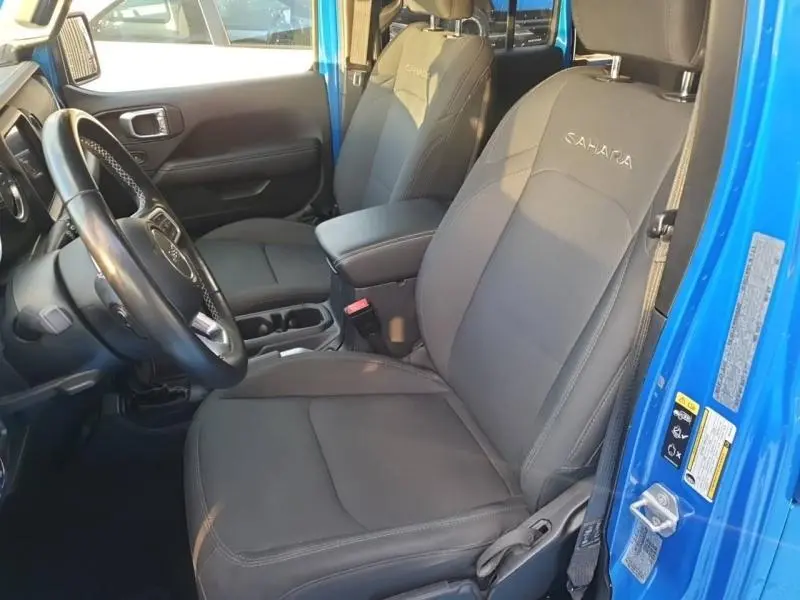 Vue intérieure côté conducteur du Jeep Wrangler Sahara Hydro Blue, sièges noirs avec logo Sahara brodé sur appuie-tête.