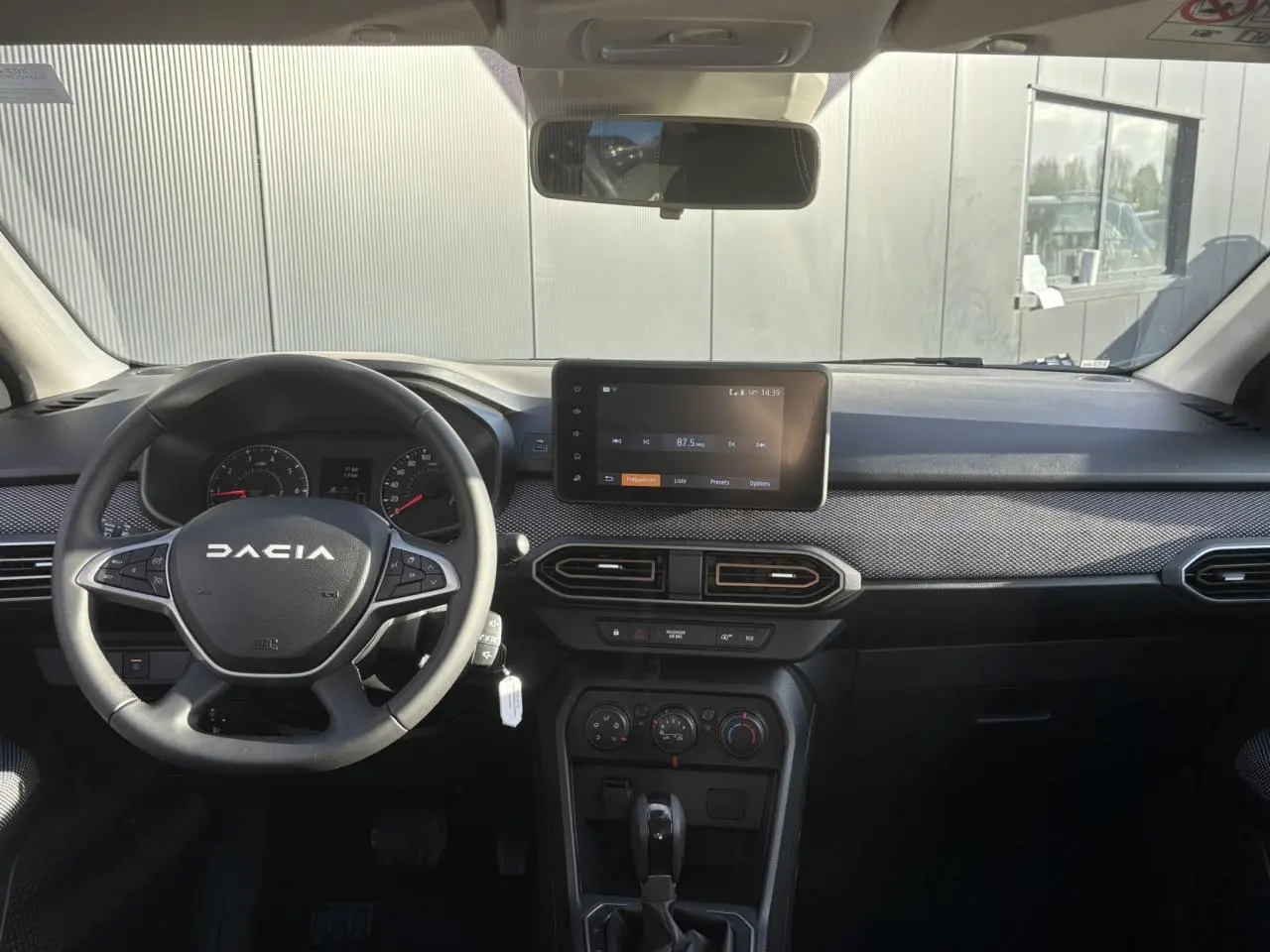 Vue frontale de l’habitacle de la Dacia Sandero Stepway blanc glacier avec tableau de bord et écran tactile central.