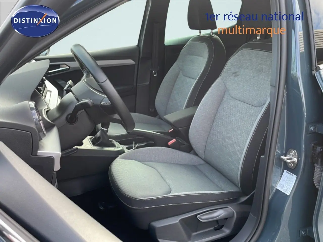 Vue intérieure côté conducteur de la SEAT Ibiza 2025 bleu fjord, montrant les sièges tissu gris et la boîte manuelle.