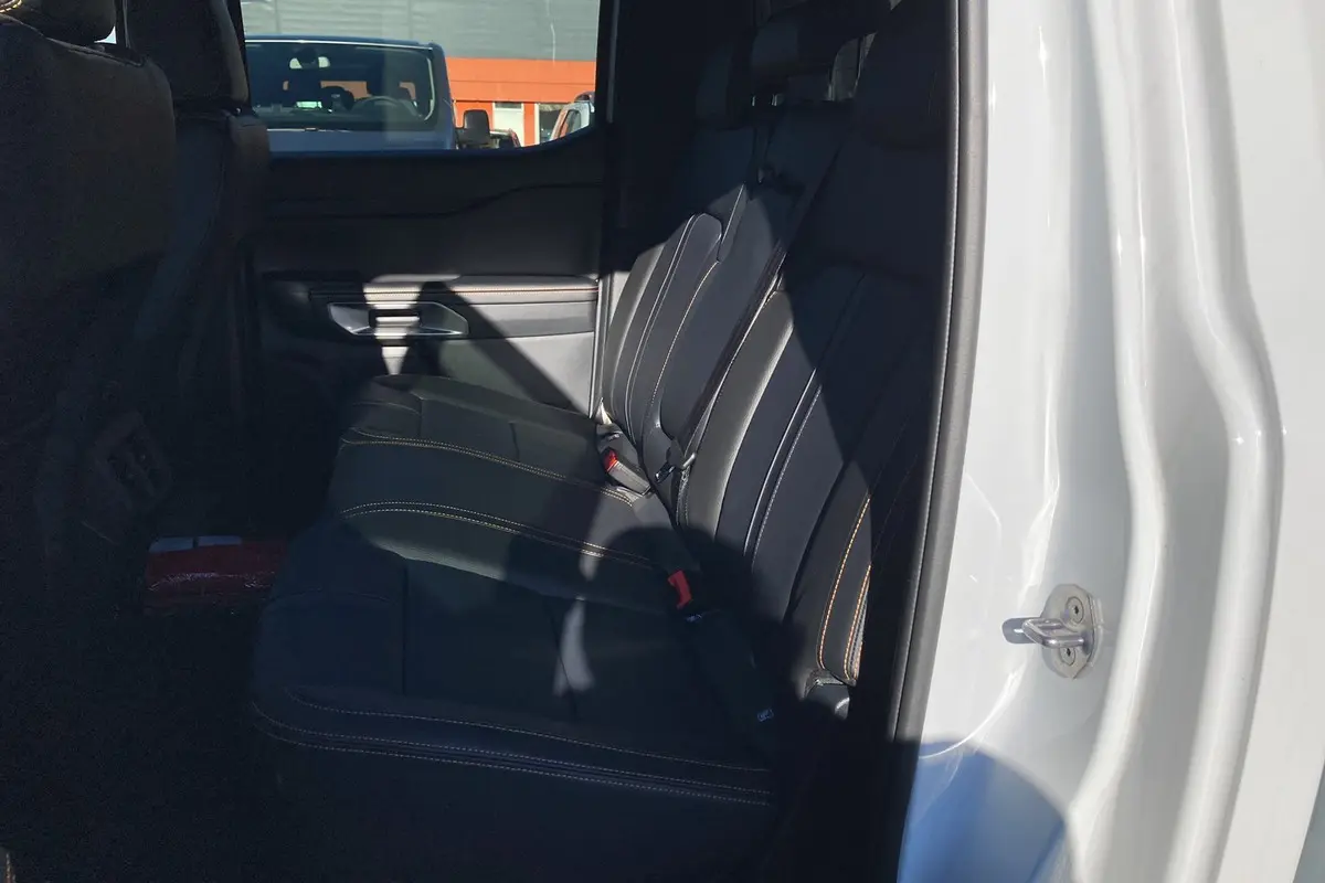 Vue intérieure côté arrière droit du Ford Ranger 2025 blanc glacier, montrant les sièges arrière en cuir noir avec surpiqûres contrastantes.