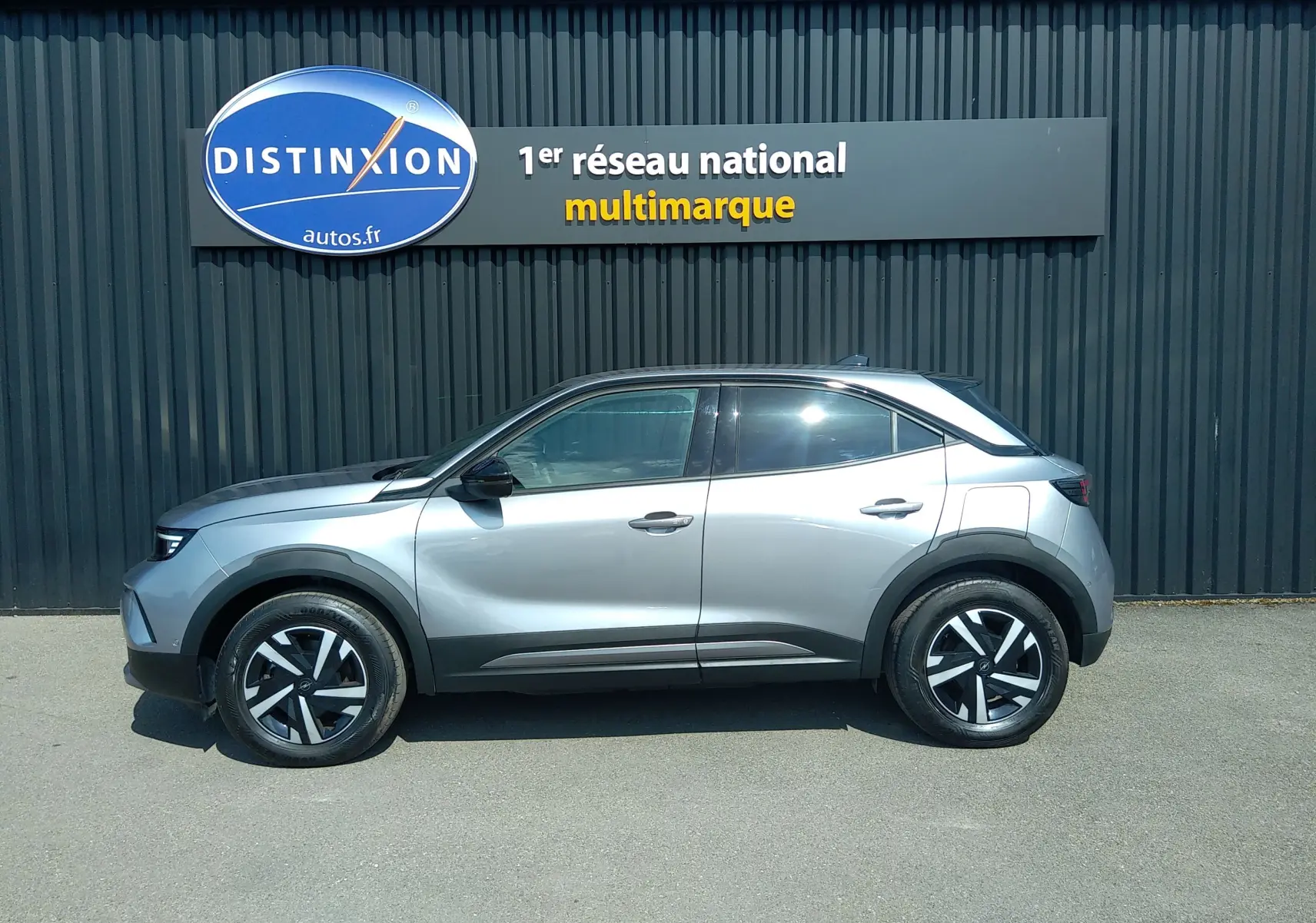 Vue latérale droite d'un Opel Mokka électrique gris 2025, avec jantes noires et détails noirs contrastants sur les passages de roues.