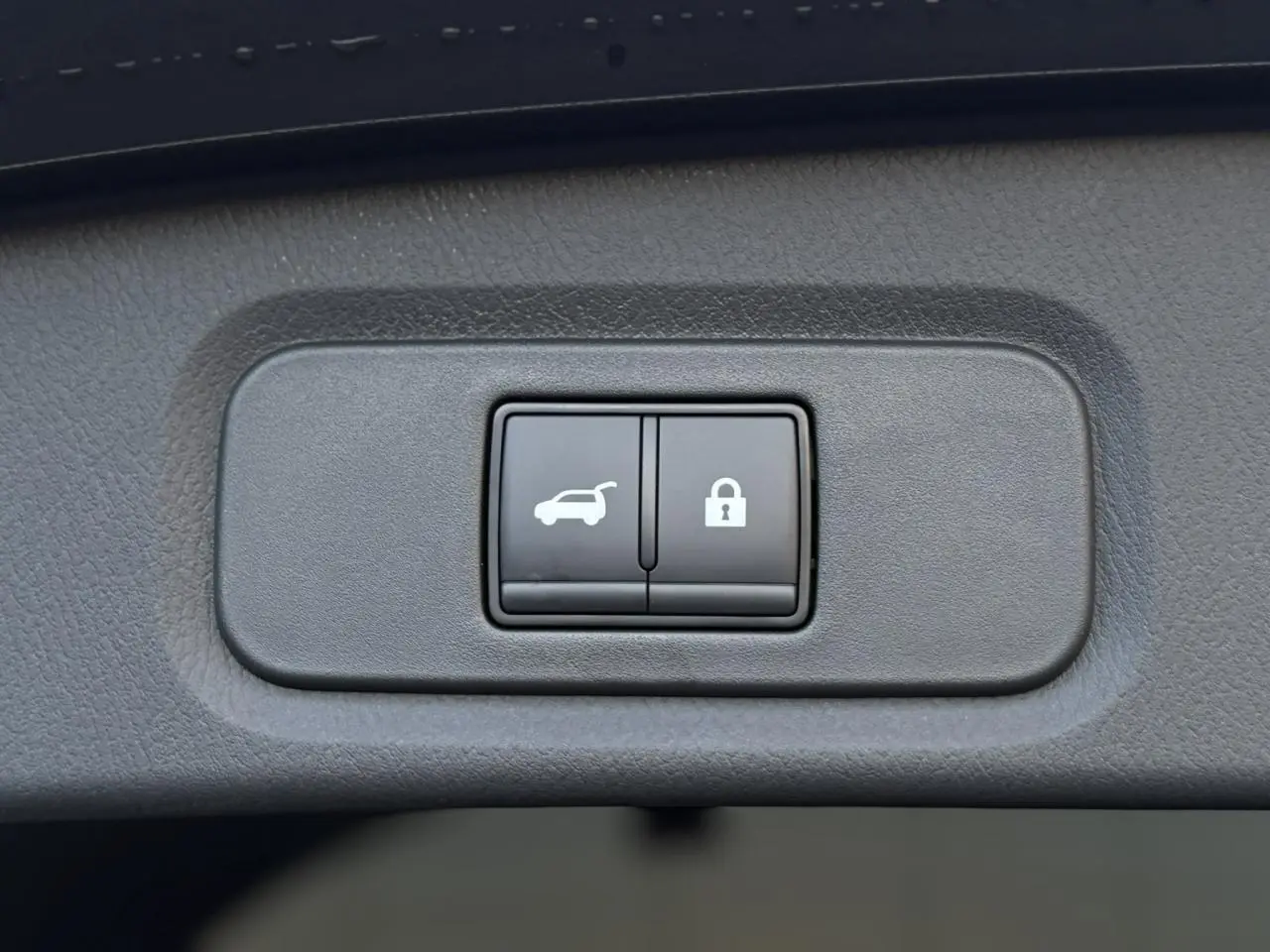 Gros plan sur les boutons d'ouverture électrique du hayon et de verrouillage du Nissan Qashqai gris Ceramic 2025.