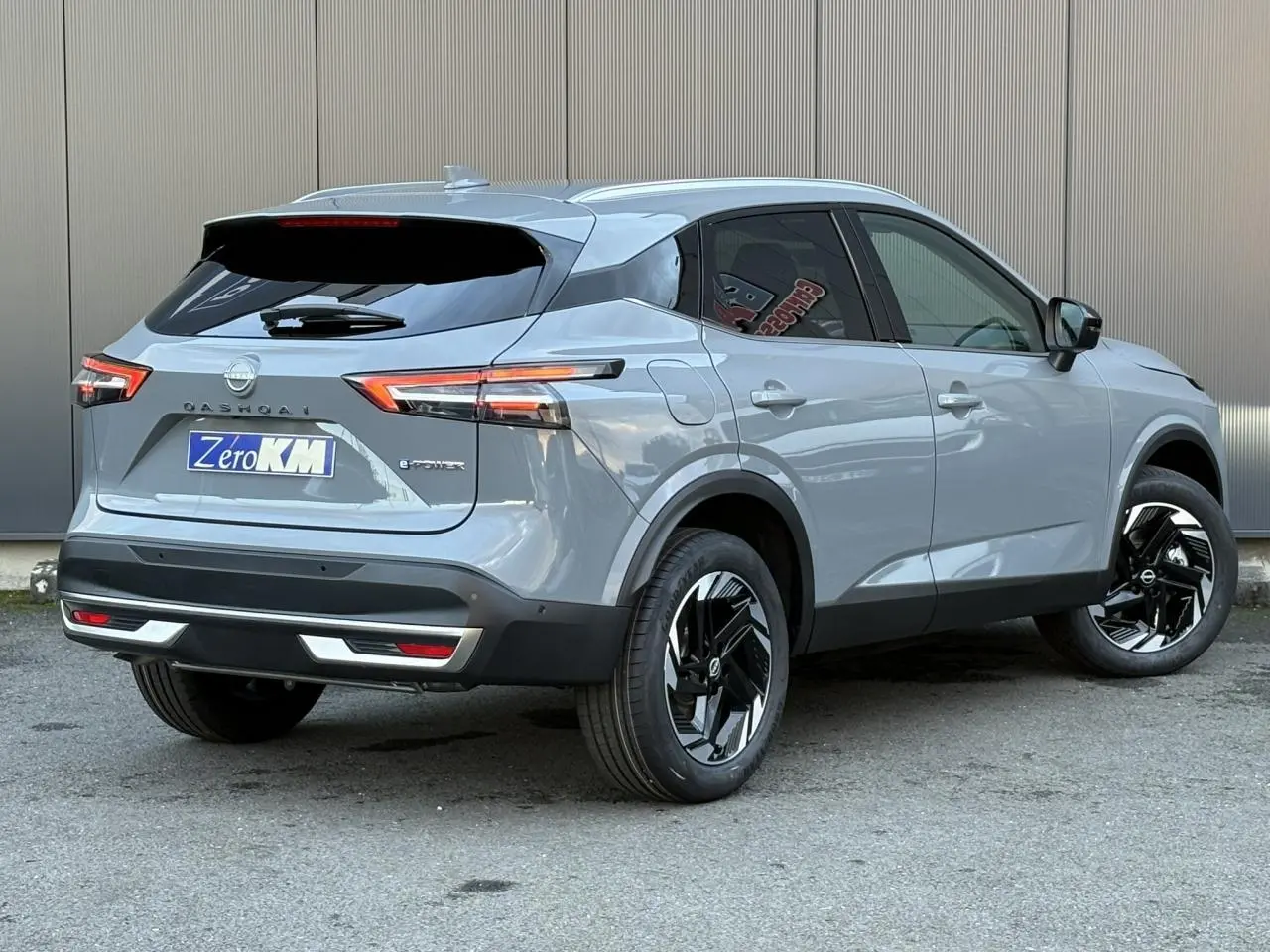 Vue 3/4 arrière droite du Nissan Qashqai 2025 gris Ceramic avec jantes alliage noires et vitres teintées.