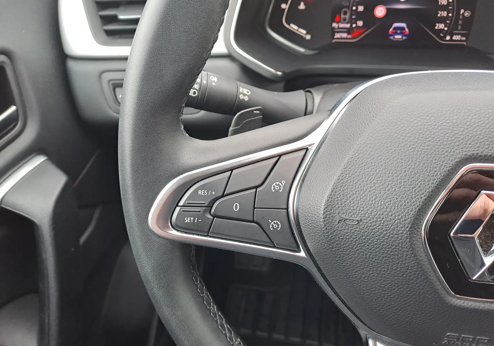 Gros plan sur le volant côté gauche du Renault Captur bleu marine 2022, avec commandes de régulateur de vitesse visibles.