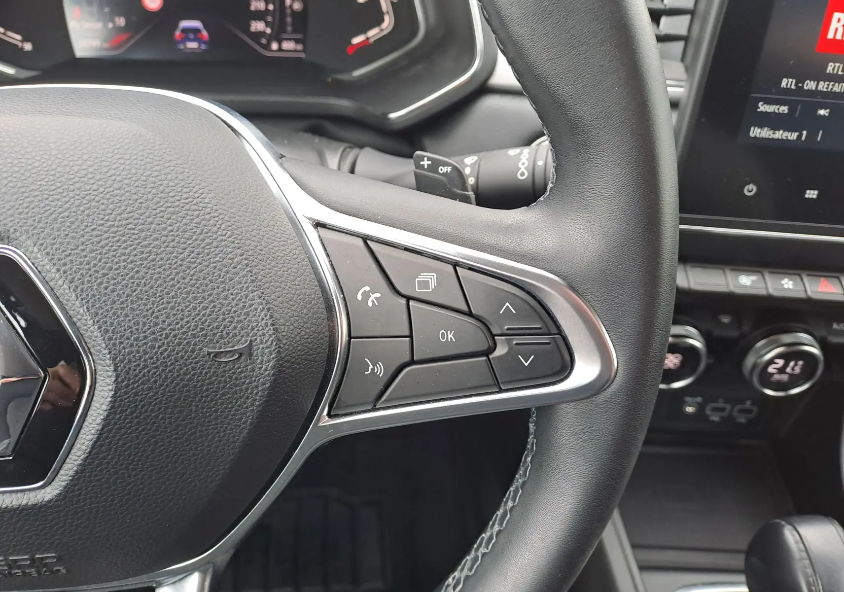 Gros plan sur le volant noir du Renault Captur 2022, montrant les commandes multifonctions à droite et le tableau de bord numérique.