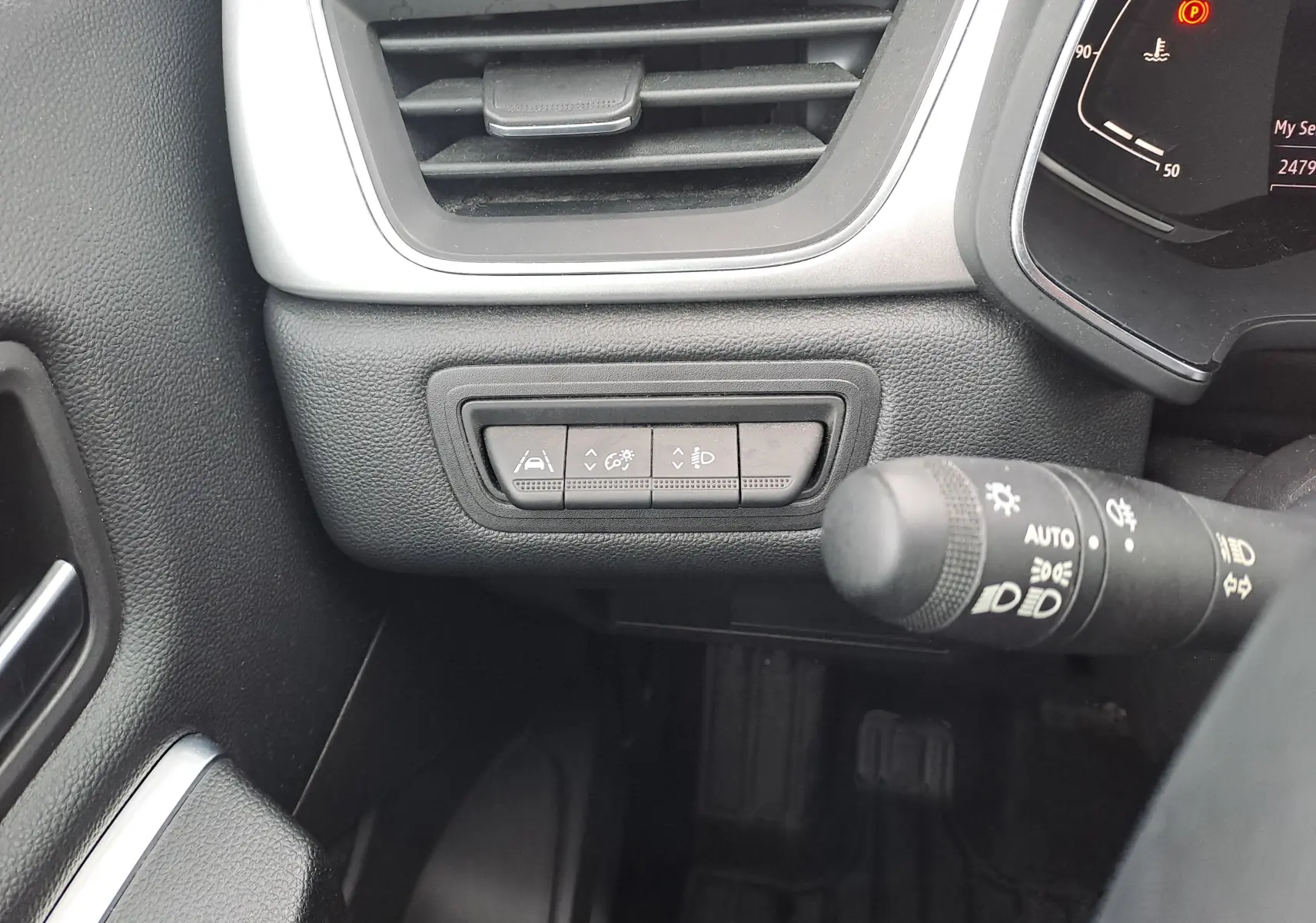 Détail intérieur côté gauche du tableau de bord du Renault Captur bleu marine 2022, avec commandes d'aide à la conduite et éclairage.
