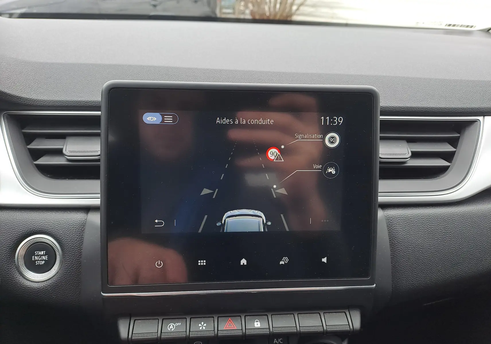 Écran tactile central du Renault Captur bleu marine 2022 montrant l'aide à la conduite et les alertes de signalisation.