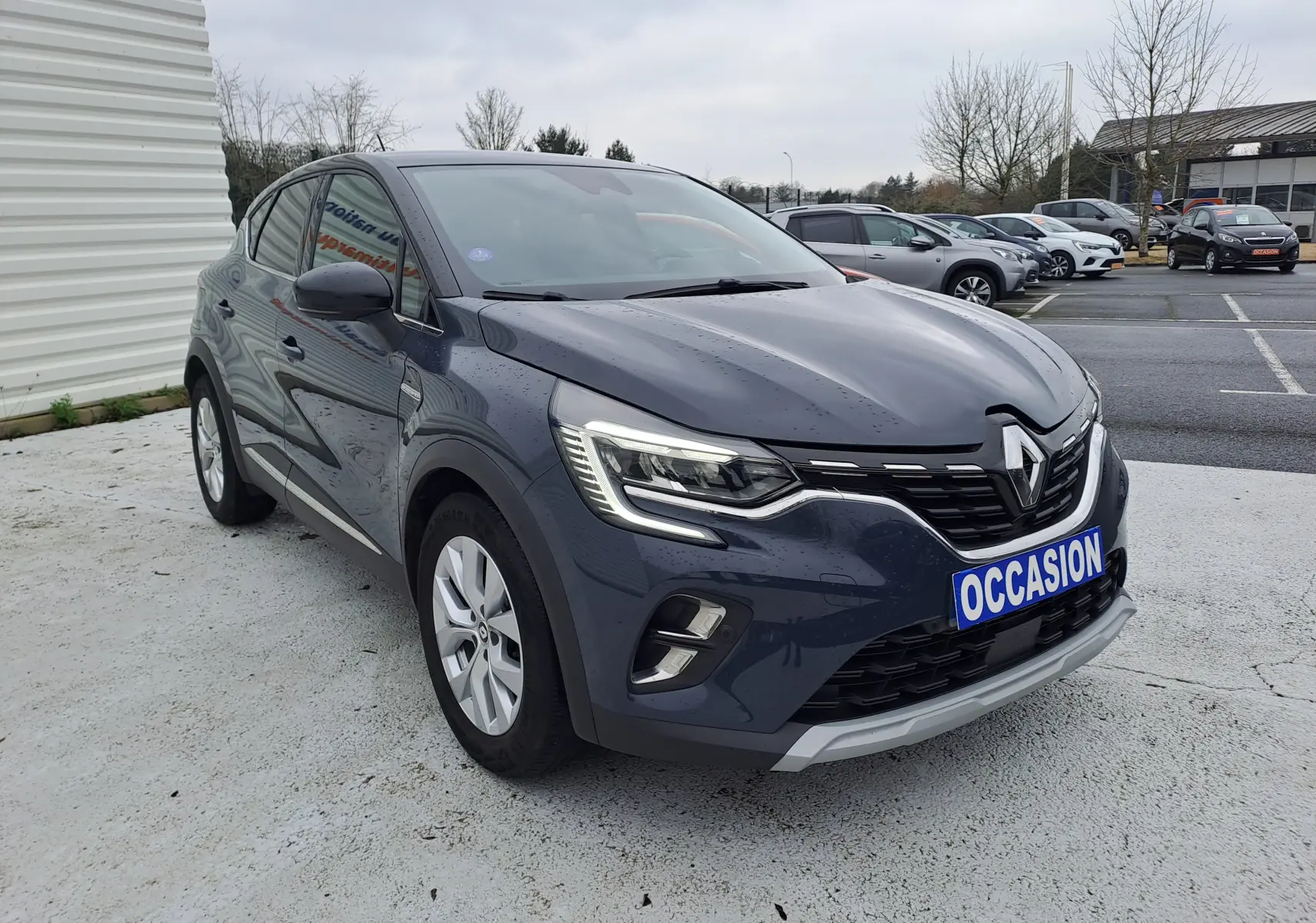 Renault Captur bleu marine 2022 en 3/4 avant droit, avec phares LED et plaque "OCCASION" visible.