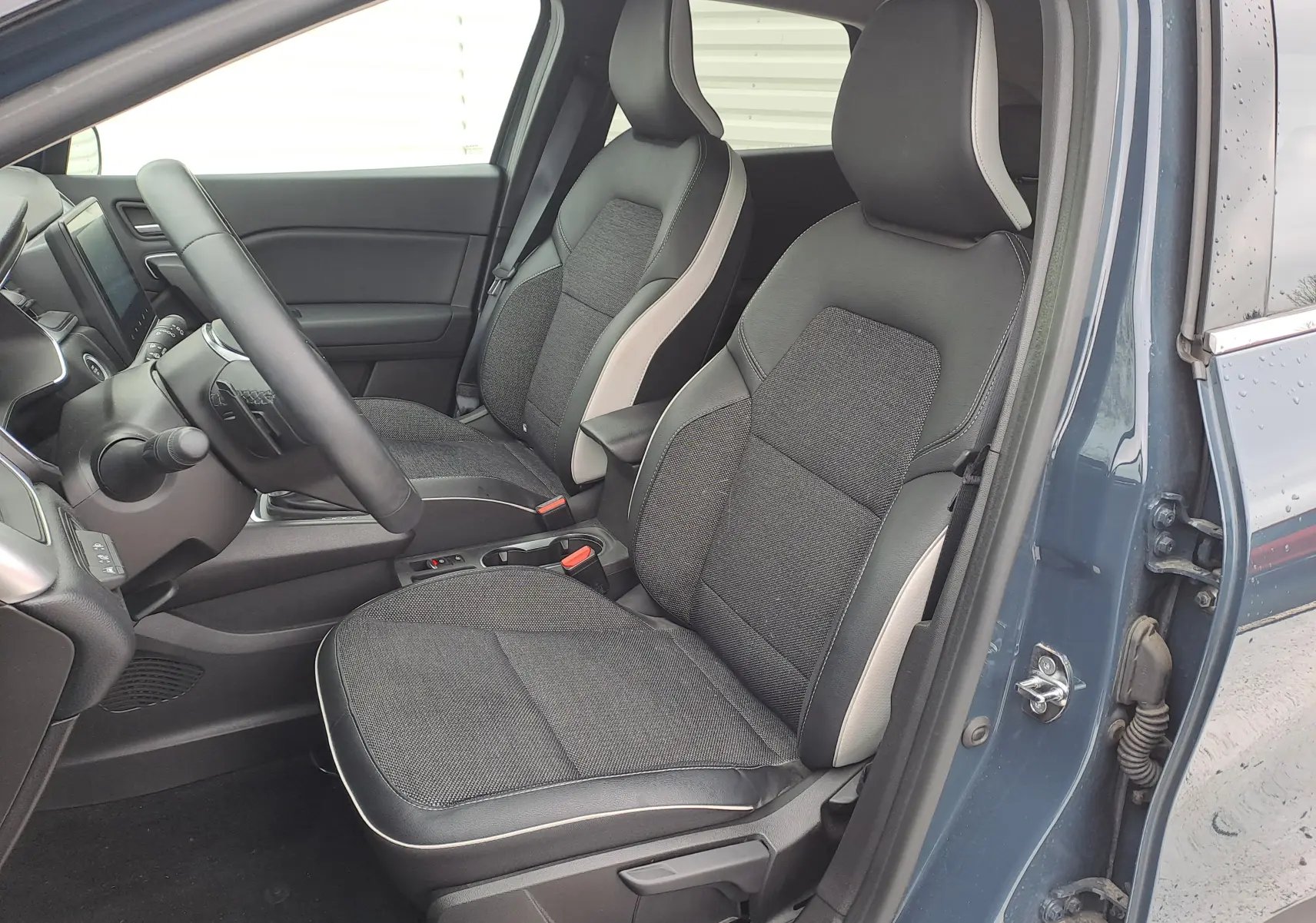 Vue intérieure côté conducteur du Renault Captur bleu marine 2022, sièges tissu noir avec surpiqûres claires.